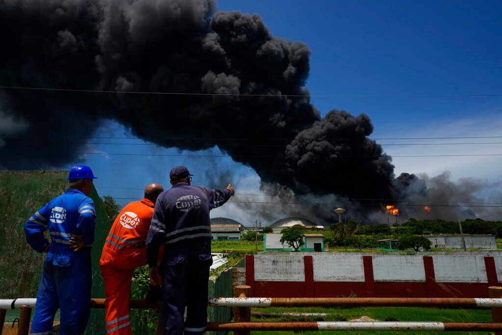Workers of the Cuba Oil Union watch a huge rising plume of smoke from the Matanzas Supertanker Base, as firefighters work to quell a blaze that began during a thunderstorm the night before, in Matazanas, Cuba, Saturday, Aug. 6, 2022. (AP Photo/Ramon Espinosa)