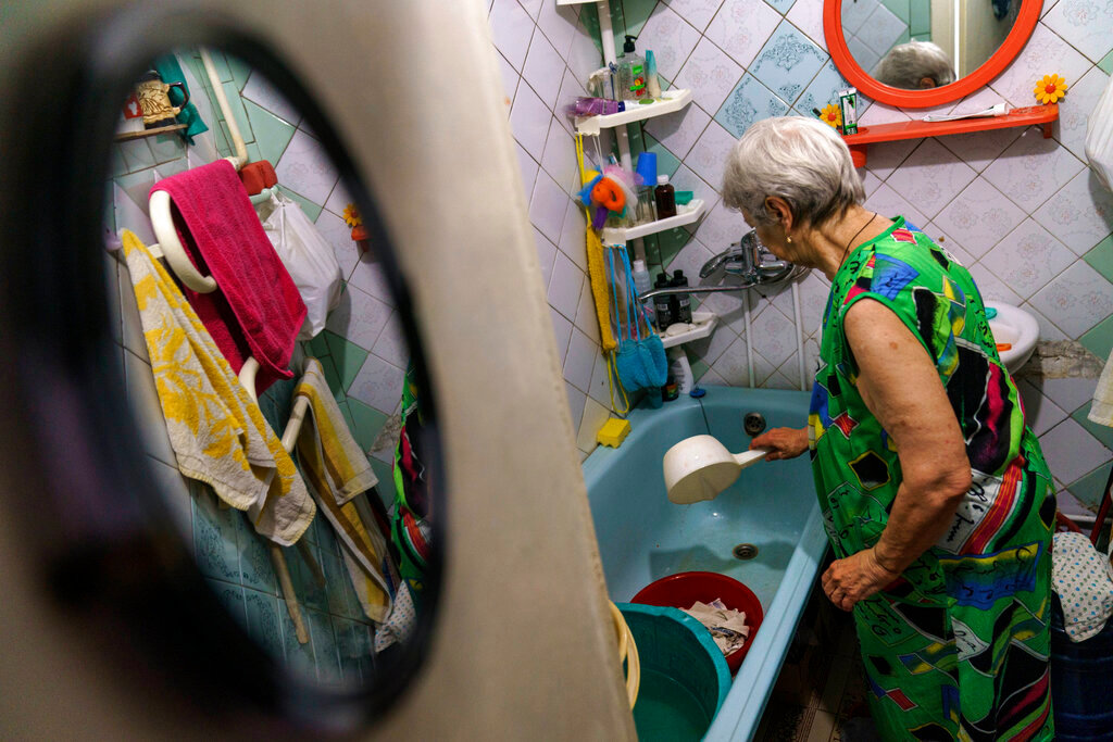 Lyubov Mahlii, 76, washes towels in her bathtub with water dragged up four flights of stairs from a public well nearby at her apartment in Sloviansk, Donetsk region, eastern Ukraine, Sunday, Aug. 7, 2022. (AP Photo/David Goldman)