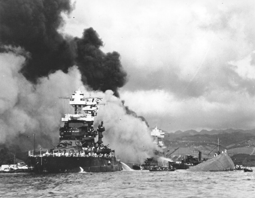 In this Dec. 7, 1941, file photo, part of the hull of the capsized USS Oklahoma is seen at right as the battleship USS West Virginia, center, begins to sink after suffering heavy damage, while the USS Maryland, left, is still afloat in Pearl Harbor, Oahu, Hawaii. (U.S. Navy via AP, File)
