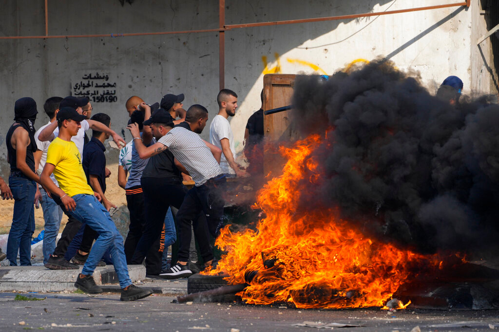Palestinian demonstrators clash with the Israeli army while forces carry out an operation in the West Bank town of Nablus, Tuesday, Aug. 9, 2022. (AP Photo/Majdi Mohammed)