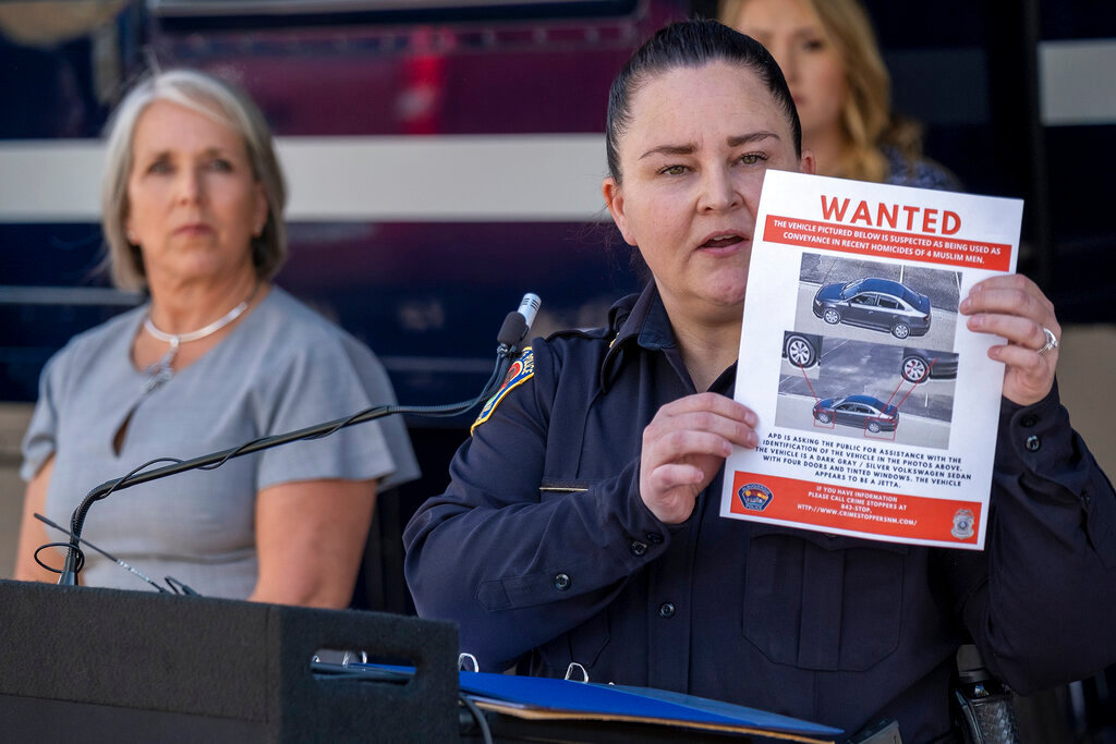 Albuquerque Police Deputy Chief of Investigations Cecily Barker holds a flyer with photos of a car wanted in connection with the murders of four Muslim men, as Governor Michelle Lujan Grisham looks on, in Albuquerque, New Mexico, Sunday, Aug. 7, 2022. (Adolphe Pierre-Louis/Albuquerque Journal via AP)