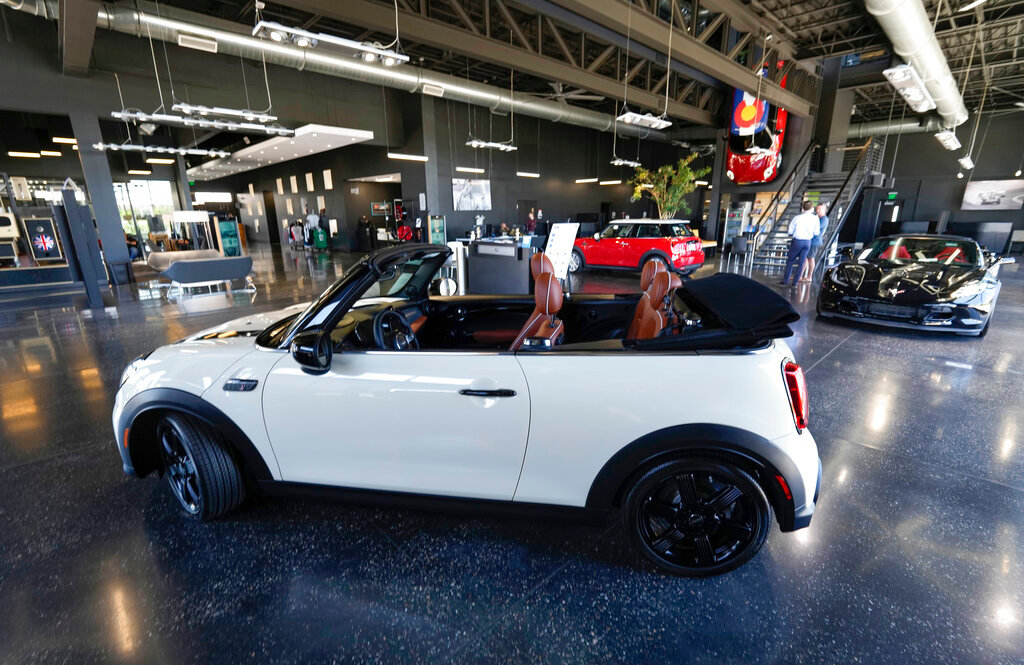 A sales associate talks with a prospective buyer of a Cooper SE electric vehicle on the showroom floor of a Mini dealership July 7, 2022, in Highlands Ranch, Colo. (AP Photo/David Zalubowski, File)