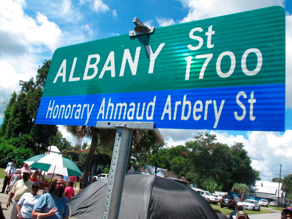 A crowd gathers under a new sign designating Albany St. as Honorary Ahmaud Arbery St. on Tuesday, Aug. 9, 2022, in Brunswick, Ga. (AP Photo/Russ Bynum)
