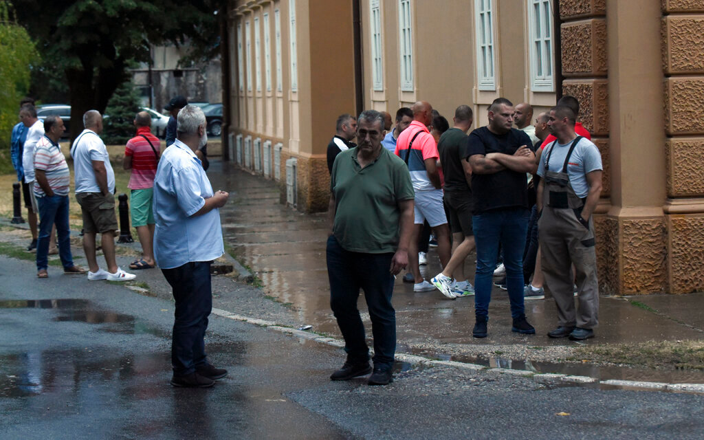 People stand at the site of a shooting rampage in Cetinje, Montenegro, Friday, Aug. 12, 2022. (AP Photo/Risto Bozovic)