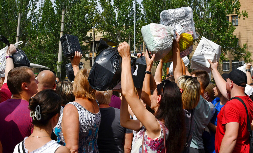 Local residents, many of whom fled the war, gather to hand out donated items such as medicines, clothes, and personal belongings to their relatives in the territories occupied by Russia, in Zaporizhzhia, Ukraine, Sunday, Aug. 14, 2022. (AP Photo/Andriy Andriyenko)