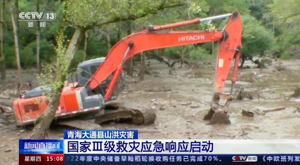An excavator tries to clear mud from an area in the aftermath of flooding in Datong county in western China's Qinghai province on Thursday, Aug. 18, 2022. (CCTV via AP)