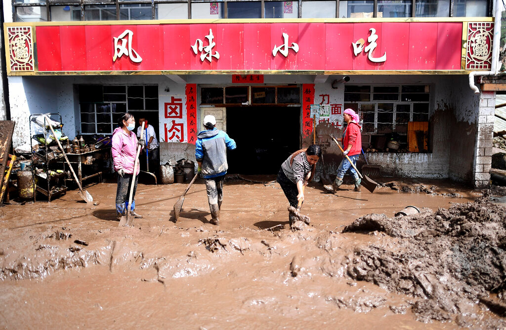 Residents clear sludge from their property in the aftermath of floods in Qingshan Township of Datong Hui and Tu Autonomous County in northwest China's Qinghai Province on Thursday, Aug. 18, 2022.(Zhang Hongxiang/Xinhua via AP)