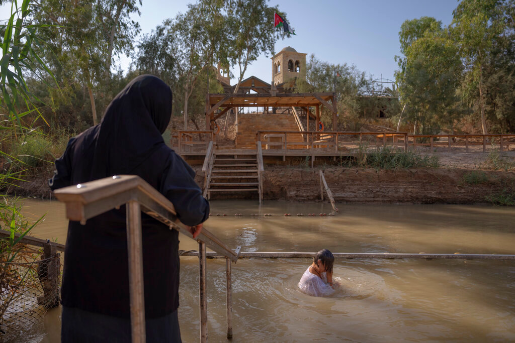 A woman stands in the Jordan River near the West Bank town of Jericho on July 31, 2022. (AP Photo/Oded Balilty)