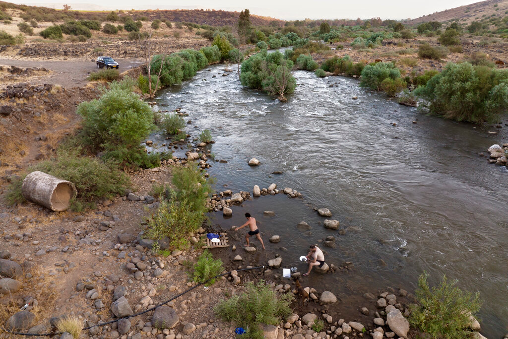 People bathe in the Jordan River near Kibbutz Karkom in northern Israel on July 30, 2022. (AP Photo/Oded Balilty)