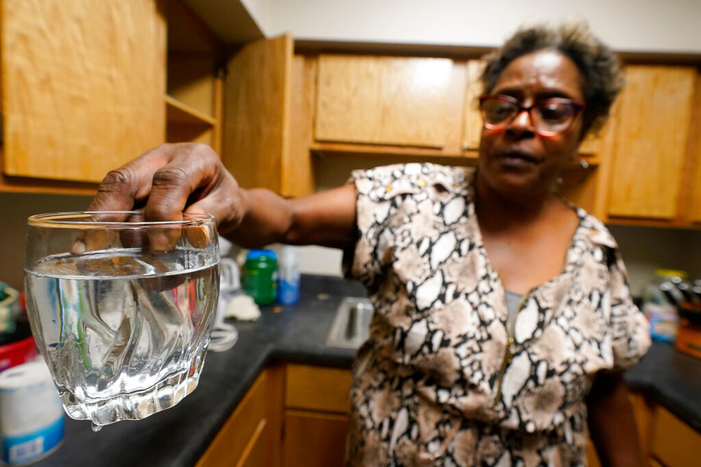Mary Gaines, a resident of the Golden Keys Senior Living apartments, displays contaminated water in her kitchen in Jackson, Miss., Thursday, Sept. 1, 2022. (AP Photo/Steve Helber)