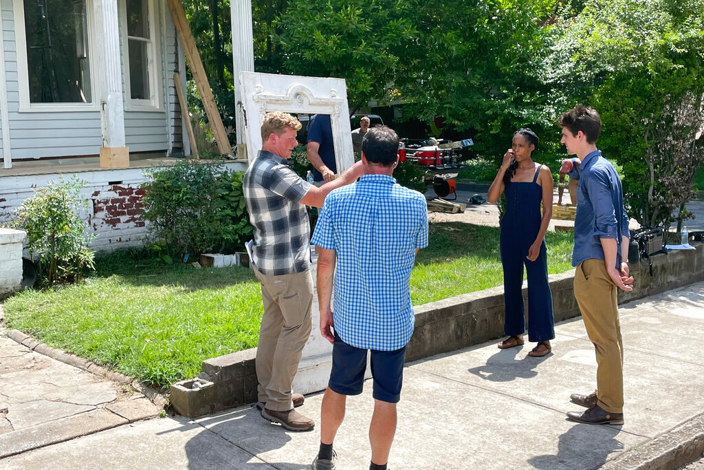"This Old House" host Kevin O'Connor, left, and homeowner Kysha Hehn, second right, prepare to install the front door in Atlanta on Aug. 10, 2022. Hehn is restoring the Victorian home of civil rights activist Luther Judson Price. (AP Photo/Michael Warren)