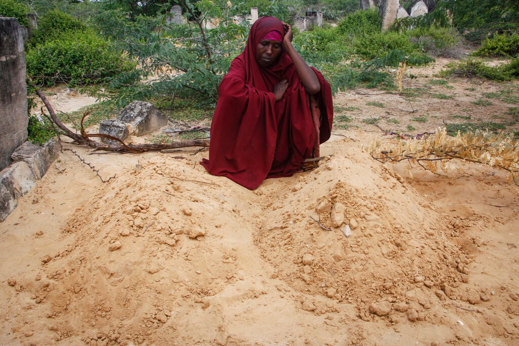 Fatuma Abdi Aliyow sits by the graves of her two sons who died of malnutrition-related diseases last week, at a camp for the displaced on the outskirts of Mogadishu, Somalia, Saturday, Sept. 3, 2022. (AP Photo/Farah Abdi Warsameh)