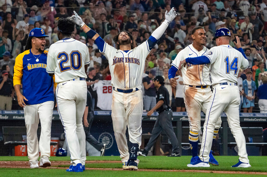 Seattle Mariners' Eugenio Suarez, center, celebrates with Luis Castillo, left, Taylor Trammell (20), Julio Rodriguez, second from right, and third base coach Manny Acta, right, after hitting a walk-off solo home run against the Atlanta Braves, Sunday, Sept. 11, 2022, in Seattle. (AP Photo/Stephen Brashear)