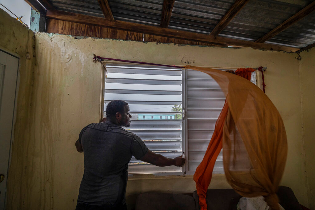 Nelson Cirino secures the windows of his home as the winds of Hurricane Fiona blow in Loiza, Puerto Rico, Sunday, Sept. 18, 2022. (AP Photo/Alejandro Granadillo)