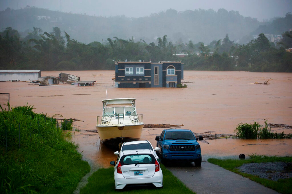 People inside a house await rescue from the floods caused by Hurricane Fiona in Cayey, Puerto Rico, Sunday, Sept.18, 2022. (AP Photo/Stephanie Rojas)