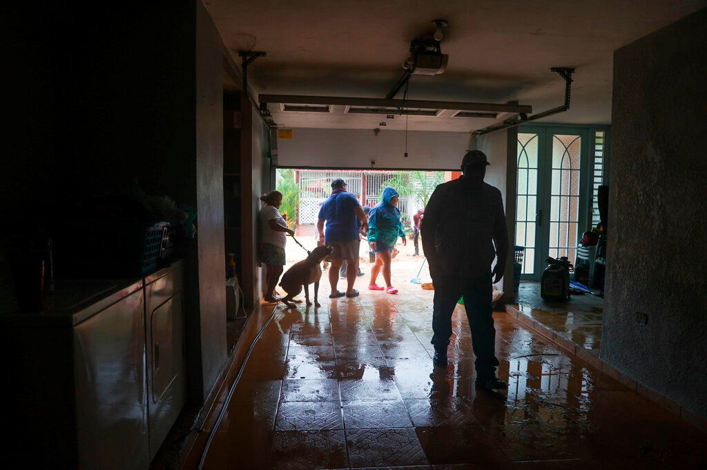 People clean a house flooded by the rains of Hurricane Fiona in Cayey, Puerto Rico, Sunday, Sept. 18, 2022. (AP Photo/Stephanie Rojas)
