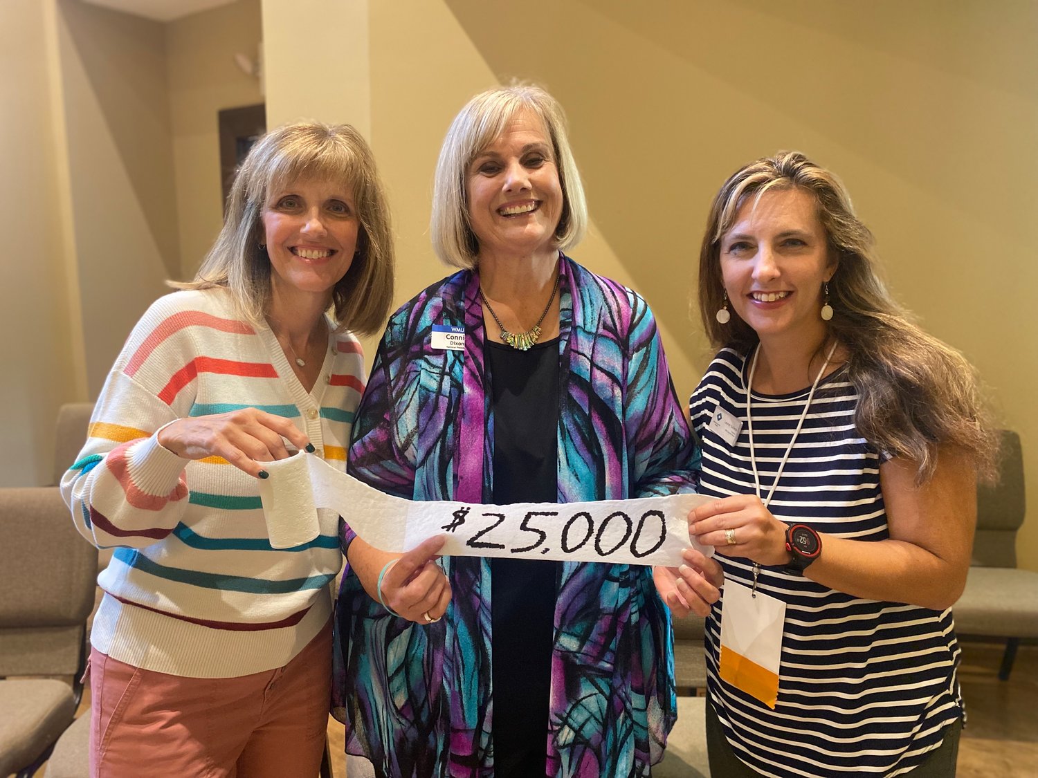 Georgians Beth Ann Williams, left, and Lauren Sullens, right, pose with national WMU President Connie Dixon and a roll of toilet paper used to  announce a $25,000 grant for Camp Pinnacle.