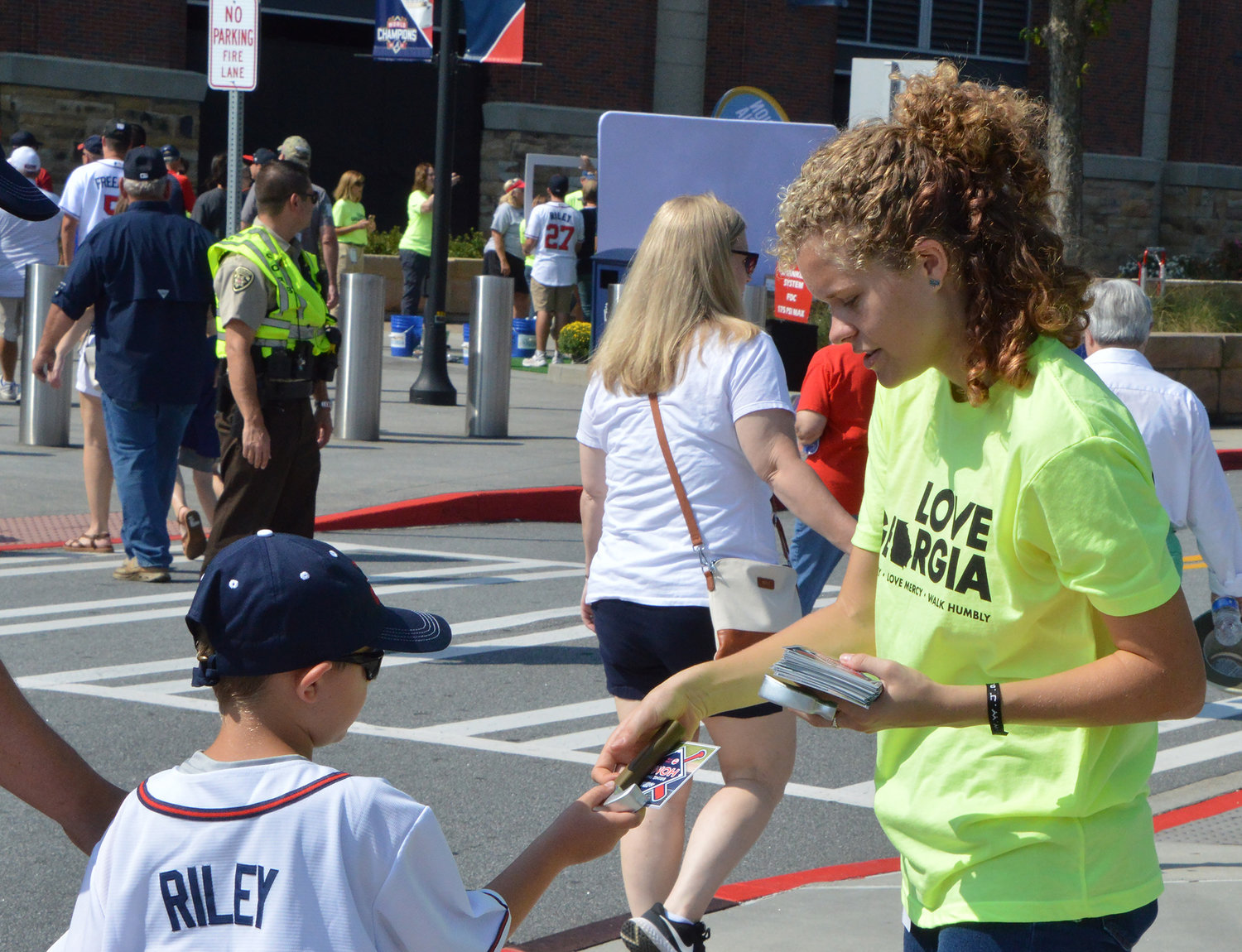 Nyah Carlson, from the Baptist Collegiate Ministry at Georgia State University, hands a hammer and pamphlet to a young fan to promote Wellspring Living, which provides housing to survivors of human trafficking, prior to the Atlanta Braves game Sunday, Sept. 18, 2022, in Atlanta. (Christian Index/Henry Durand)