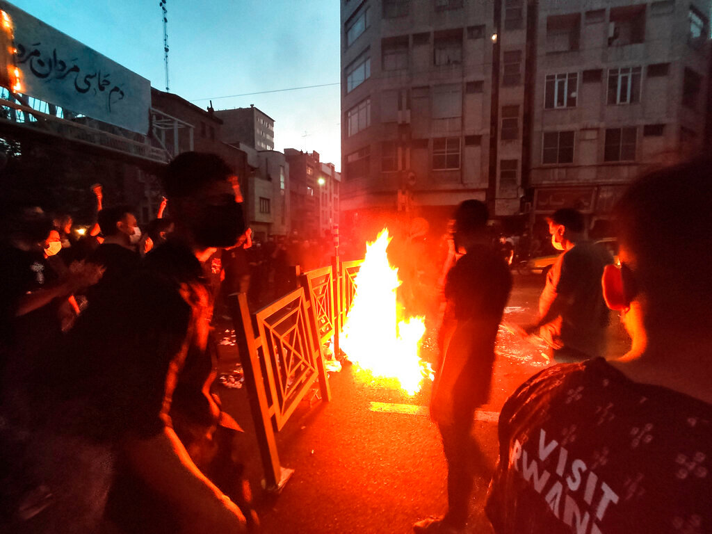 Protesters make a fire and block the street during a protest over the death of a woman who was detained by the morality police, in downtown Tehran, Iran, Wednesday, Sept. 21, 2022. (AP Photo)