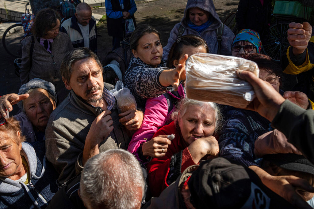 Local residents receive humanitarian aid distributed by volunteers in the recently retaken area of Izium, Ukraine, Wednesday, Sept. 21, 2022. (AP Photo/Evgeniy Maloletka)