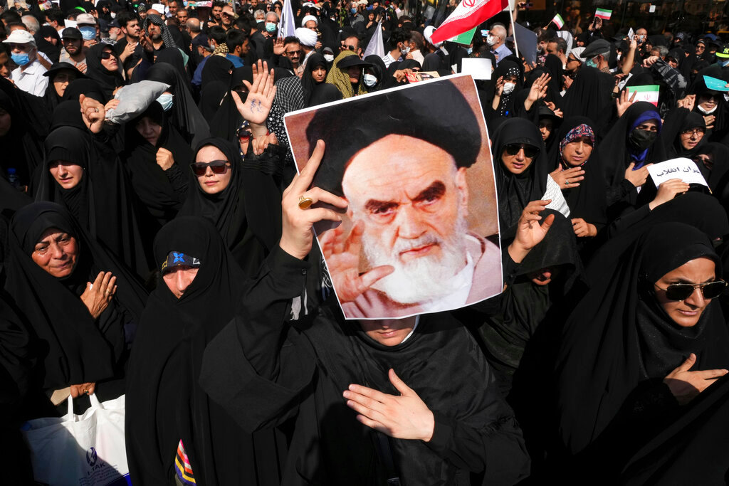 A pro-government demonstrator holds a poster of the late Iranian revolutionary founder Ayatollah Khomeini while attending a rally after the Friday prayers to condemn recent anti-government protests over the death of a young woman in police custody, in Tehran, Iran, Friday, Sept. 23, 2022. (AP Photo/Vahid Salemi)