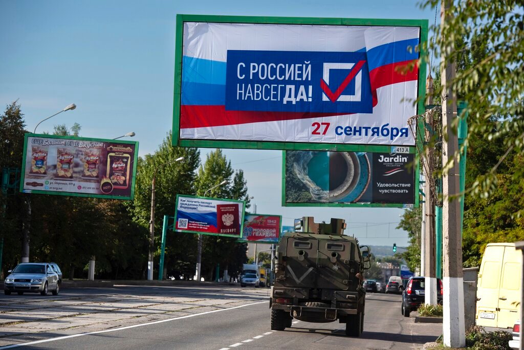 A military vehicle drives along a street with a billboard that reads: "With Russia forever, September 27", prior to a referendum in Luhansk, Ukraine, Thursday, Sept. 22, 2022. (AP Photo)