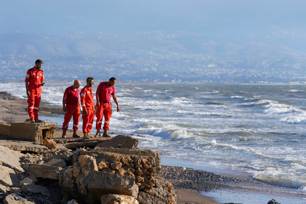 Palestinian rescue team members stand on the Lebanese shore as they wait to receive the bodies of victims who were on a boat carrying migrants from Lebanon that sank in Syrian waters, at Arida border crossing point between Lebanon and Syria, north Lebanon, Sept. 23, 2022. (AP Photo/Bilal Hussein)