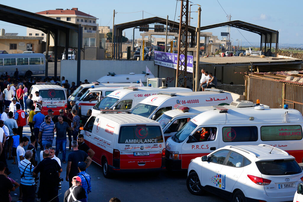 Lebanese and Palestinian ambulances wait to receive the bodies of victims from a boat carrying migrants from Lebanon that sank in Syrian waters, at Arida border crossing point between Lebanon and Syria, north Lebanon, Sept. 23, 2022. (AP Photo/Bilal Hussein)