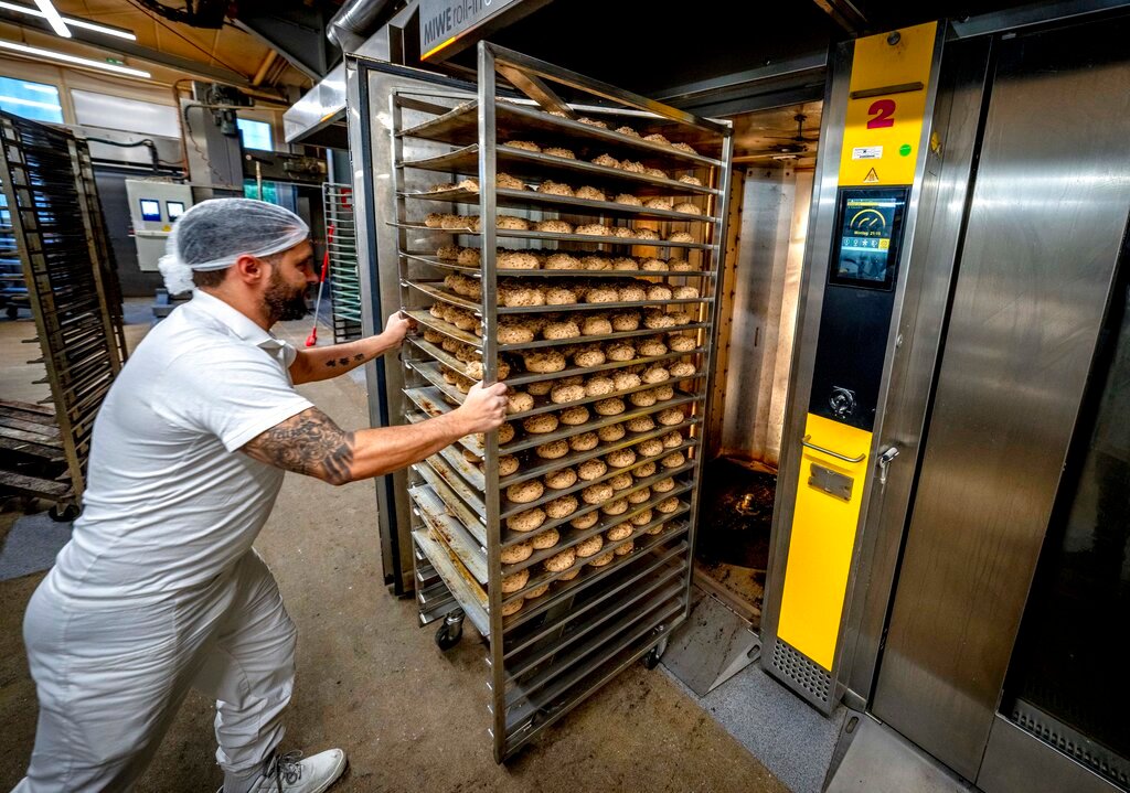 An employee pushes rolls into one of the gas-heated ovens in a production facility in Neu Isenburg, Germany, Monday, Sept. 19, 2022. Andreas Schmitt, head of the local bakers' guild, said some small bakeries are contemplating giving up due to the energy crisis. (AP Photo/Michael Probst)