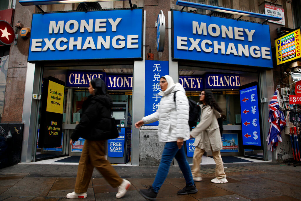 People walk past a currency exchange bureau in London, Monday, Sept. 26, 2022. (AP Photo/David Cliff)