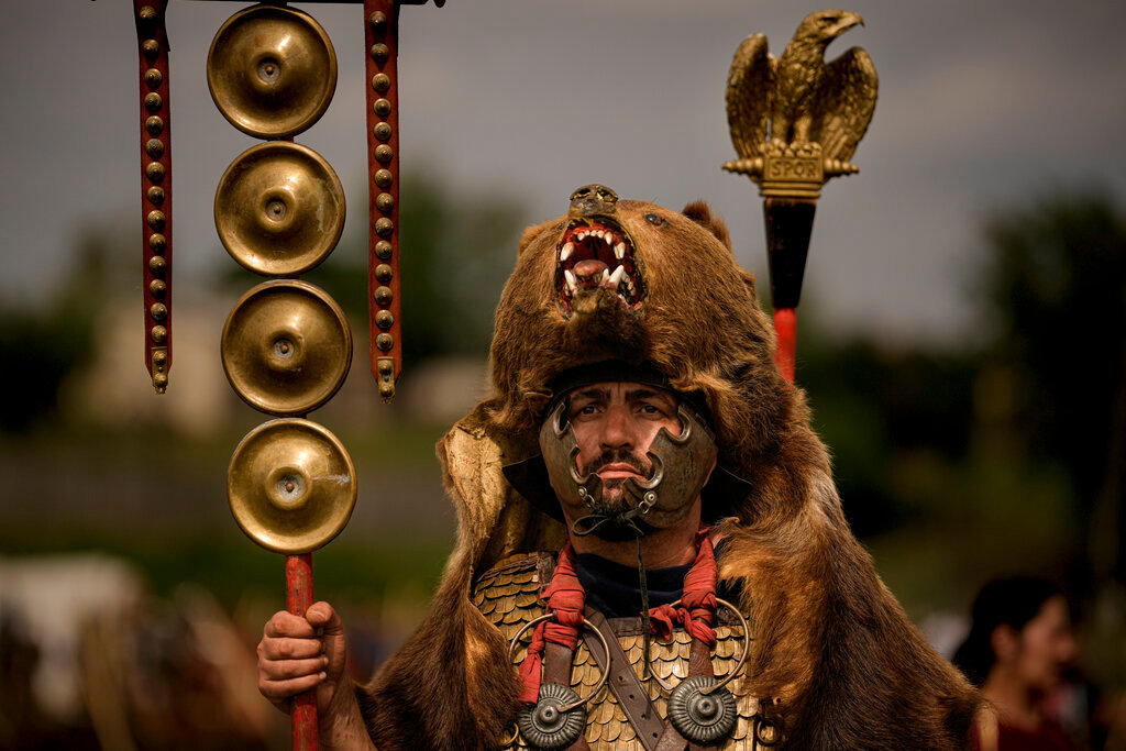 A participant in the Romula Fest historic reenactment event, wearing a Roman legion uniform and a bear fur stands in the village of Resca, Romania, Sunday, Sept. 4, 2022. (AP Photo/Andreea Alexandru)