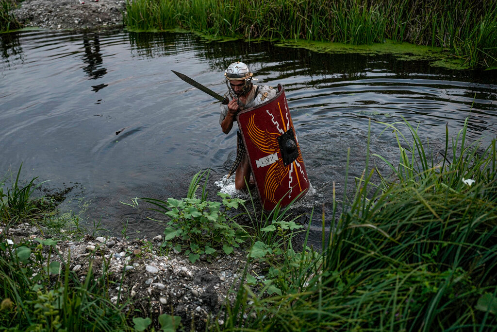 A man wearing a Roman soldier outfit walks after falling into a river during a battle at the Romula Fest historic reenactment festival in the village of Resca, Romania, Saturday, Sept. 3, 2022. (AP Photo/Andreea Alexandru)