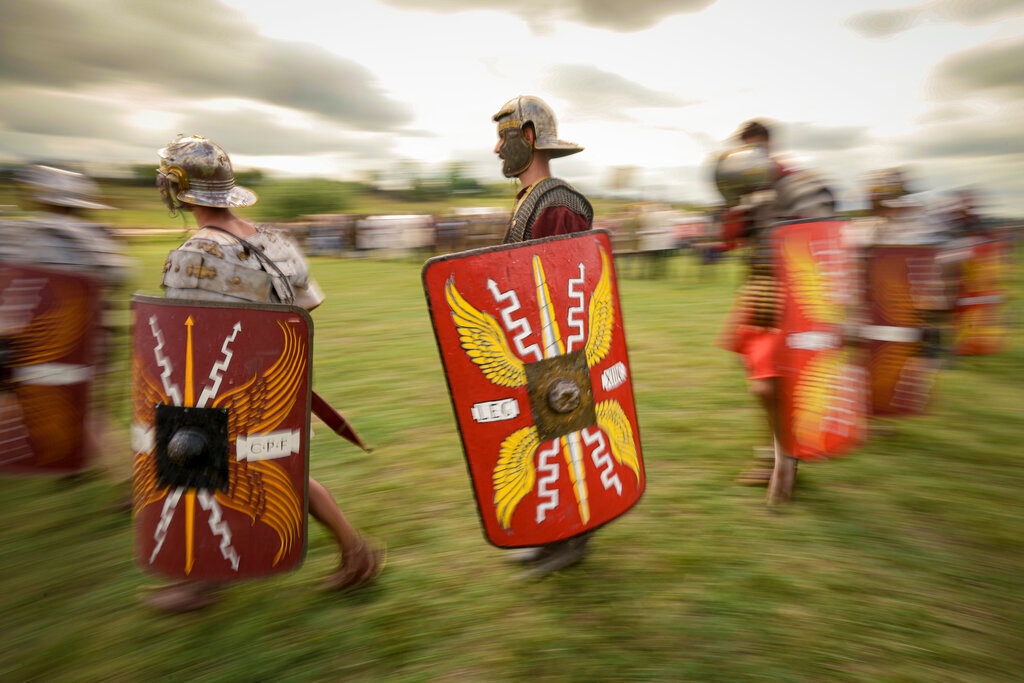 Men wearing Roman soldiers' outfits walk during a battle at the Romula Fest historic reenactment festival in the village of Resca, Romania, Sunday, Sept. 4, 2022. (AP Photo/Andreea Alexandru)