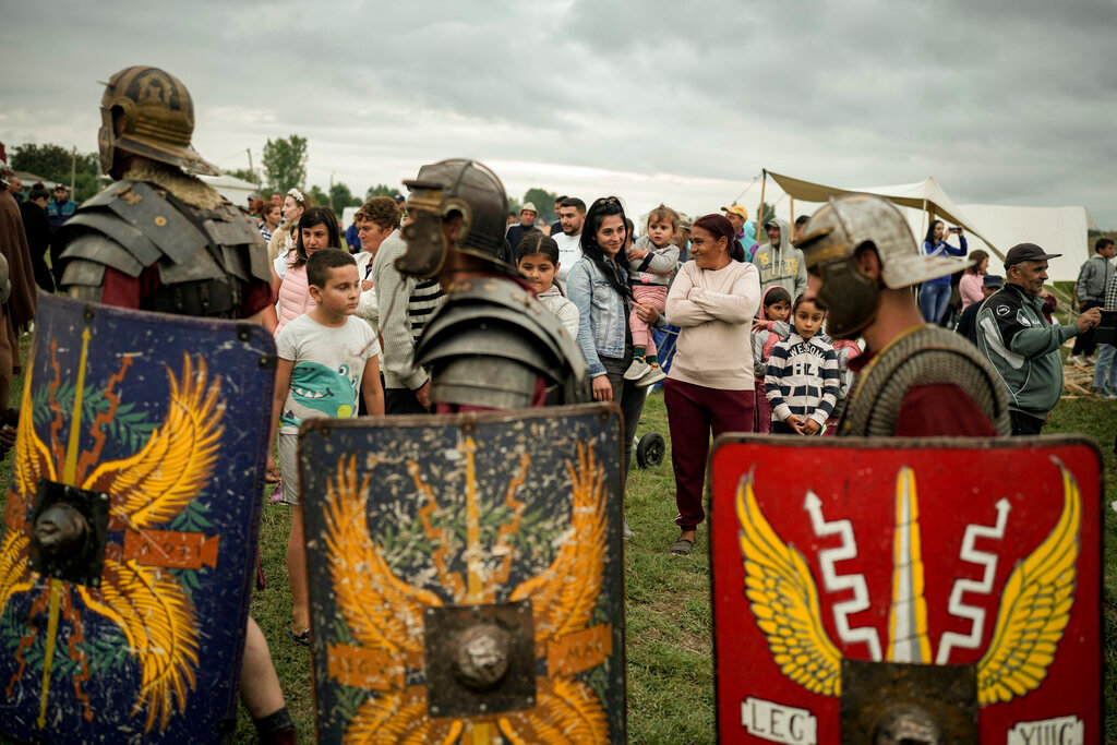 Men wearing Roman soldiers' outfits walk past the public during the Romula Fest historic reenactment event in the village of Resca, Romania, Saturday, Sept. 3, 2022. (AP Photo/Andreea Alexandru)