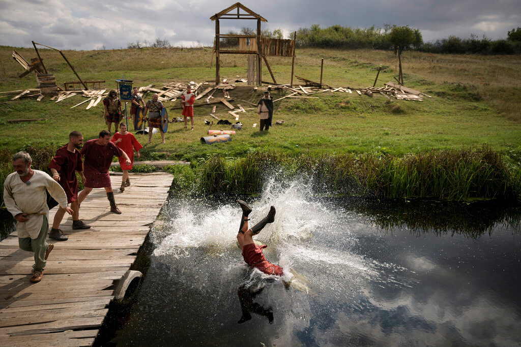 A man wearing a Roman soldier outfit is thrown into a river during a battle at the Romula Fest historic reenactment festival in the village of Resca, Romania, Sunday, Sept. 4, 2022. (AP Photo/Andreea Alexandru)