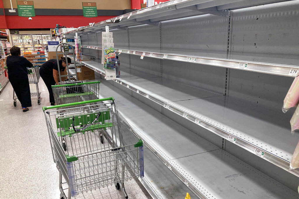As Hurricane Ian approaches Florida, shopping carts are left abandoned next to empty shelves that stock bottled water at a supermarket Monday, Sept. 26, 2022, in Orlando, Fla.  (AP Photo/John Raoux)