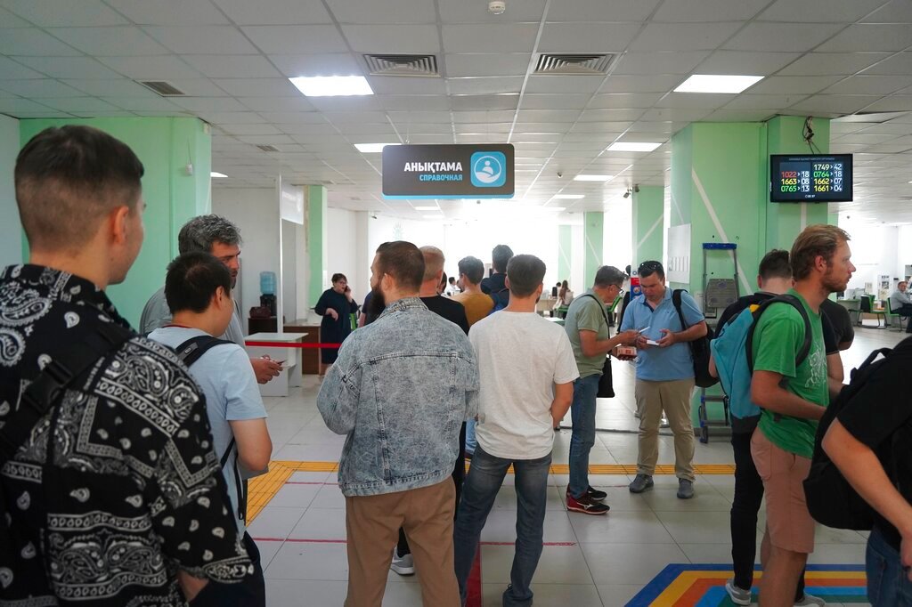 Russian men line up to get a Kazakhstan Personal Identification Number in a public service center in Almaty, Kazakhstan, Tuesday, Sept. 27, 2022. (Vladimir Tretyakov/NUR.KZ via AP)
