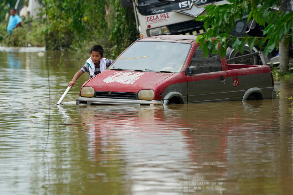 A boy plays along a flooded street from Typhoon Noru in San Miguel, Bulacan province, Philippines, Monday, Sept. 26, 2022. (AP Photo/Aaron Favila)