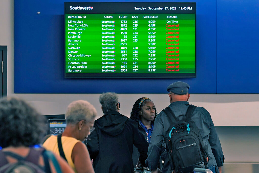 Southwest Airline passengers check into a ticket counter near a sign that shows canceled flights at the Tampa International Airport Tuesday, Sept. 27, 2022, in Tampa, Fla. (AP Photo/Chris O'Meara)