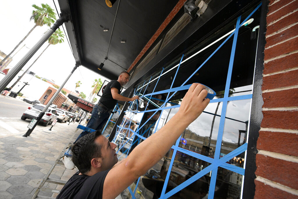 Lukas Berlajolli, above, and Tony Fazliu help tape up the windows of a pizza restaurant in the Ybor City district in preparation for Hurricane Ian as the storm approaches the western side of the state, Tuesday, Sept. 27, 2022, in Tampa, Fla. (AP Photo/Phelan M. Ebenhack)