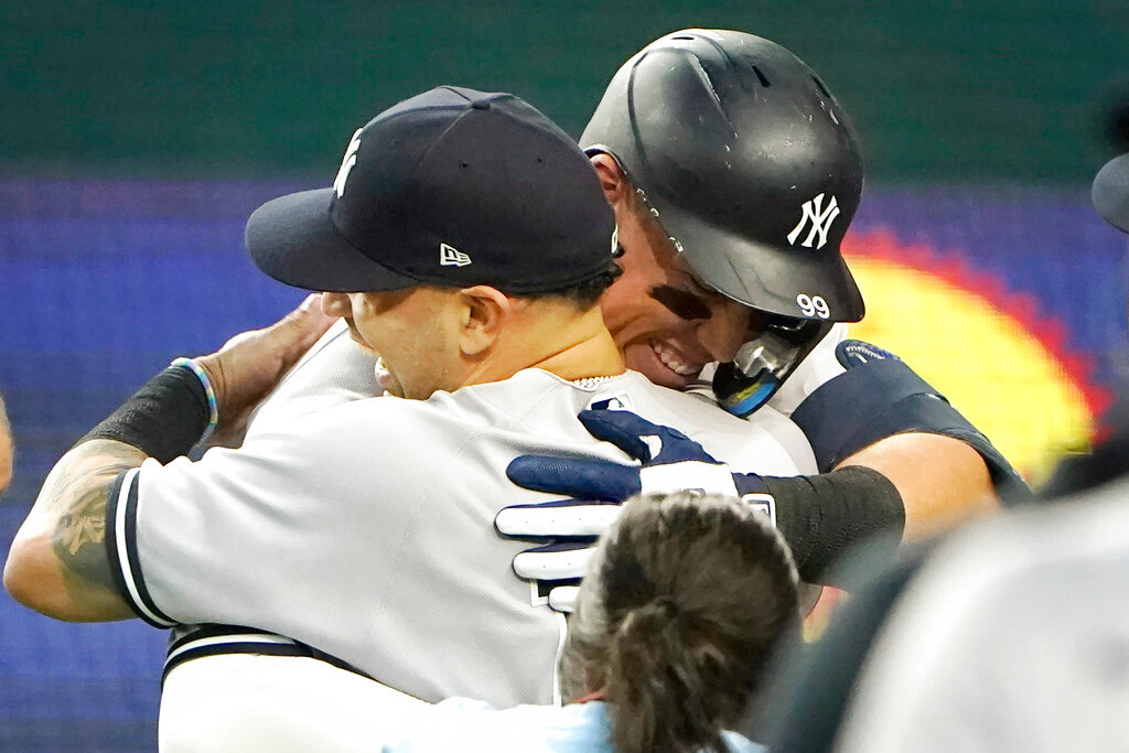 New York Yankees' Aaron Judge, right, hugs teammates after hitting a solo home run, his 62nd of the season, during the first inning against the Texas Rangers in Arlington, Texas, Tuesday, Oct. 4, 2022. (AP Photo/LM Otero)