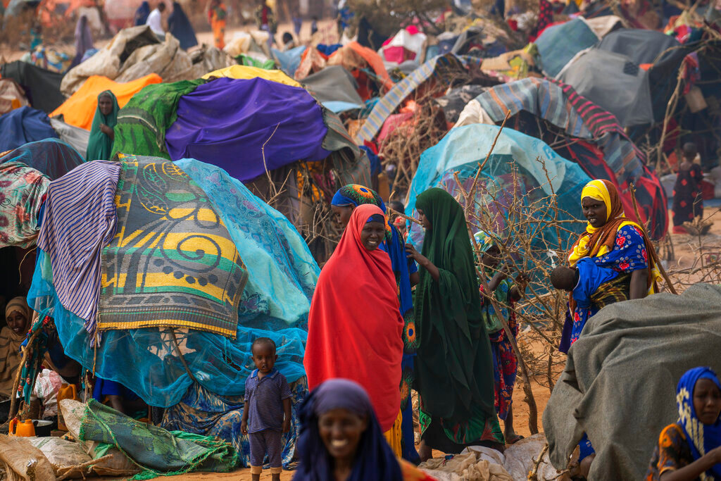 People walk through a displacement camp on the outskirts of Dollow, Somalia, Sept. 19, 2022. (AP Photo/Jerome Delay)