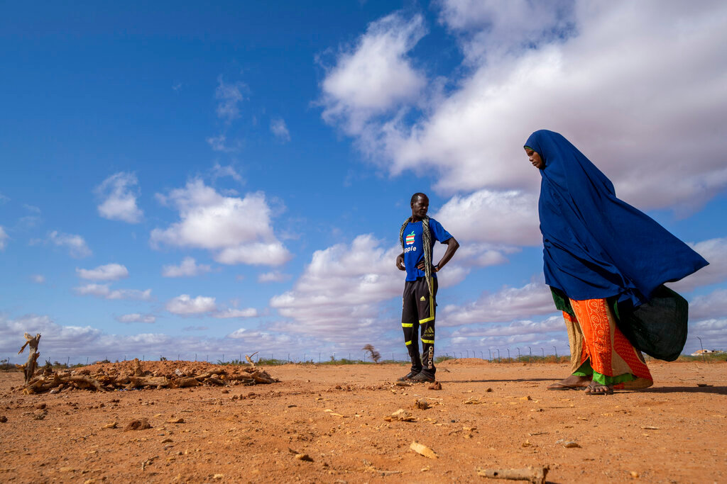 Fartum Issack, right, and her husband, Adan, stand by the grave of their 1-year-old daughter at a displacement camp on the outskirts of Dollow, Somalia, Sept. 19, 2022. (AP Photo/Jerome Delay)