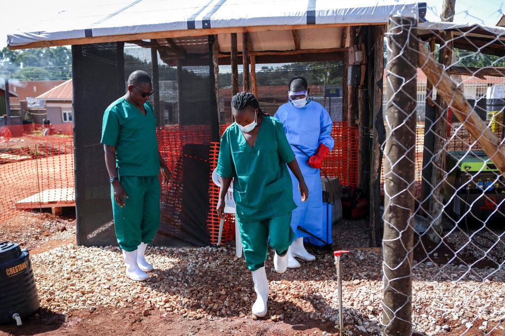A medical attendant disinfects the rubber boots of a medical officer before leaving the Ebola isolation section of Mubende Regional Referral Hospital, in Mubende, Uganda, Sept. 29, 2022. (AP Photo/Hajarah Nalwadda)
