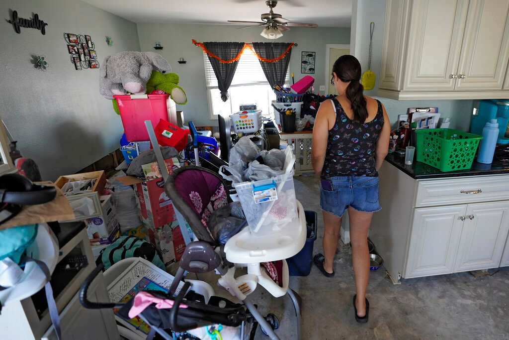 Christina Barrett walks through her waterlogged belongings at her home, Tuesday, Oct. 4, 2022, in North Port, Fla. (AP Photo/Chris O'Meara)