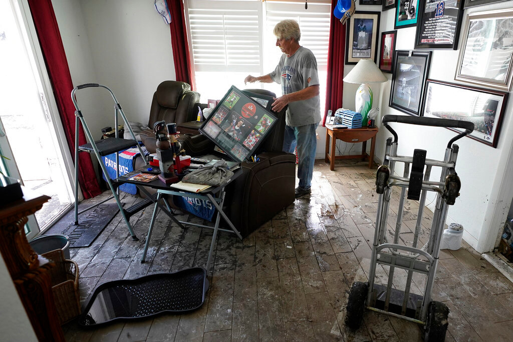 Ron Audette removes waterlogged photos from the walls of his damaged home Tuesday, Oct. 4, 2022, in North Port, Fla. (AP Photo/Chris O'Meara)