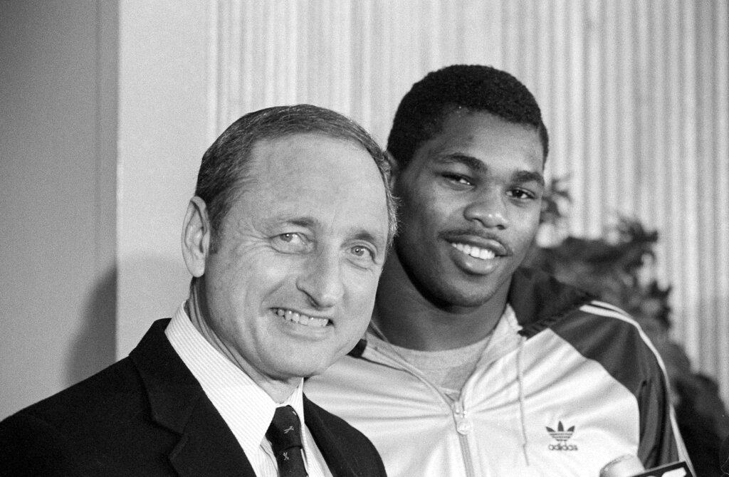 Georgia running back Herschel Walker, right, brings a smile to the face of his coach Vince Dooley as he announces that he would play football next year at Georgia rather than the USFL, Feb. 8, 1983, in  Athens, Ga. (AP Photo/Joe Holloway Jr., File)