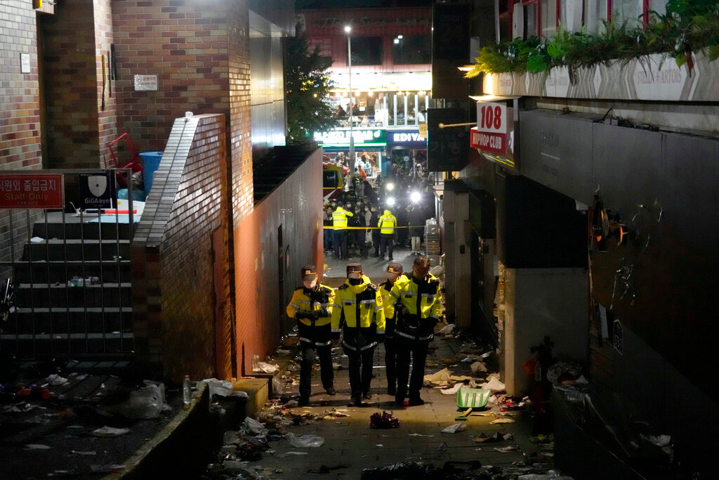 Police officers inspect the scene where people died and were injured in Seoul, South Korea, Sunday, Oct. 30, 2022, after a mass of mostly young people celebrating Halloween festivities in Seoul became trapped and crushed as the crowd surged into a narrow alley. (AP Photo/Ahn Young-joon)