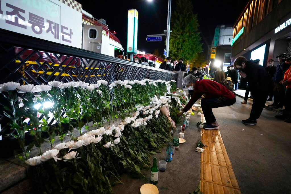 A woman places flowers at a tribute for victims near the scene of a deadly accident in Seoul, South Korea, Sunday, Oct. 30, 2022, following Saturday night's Halloween festivities. (AP Photo/Ahn Young-joon)
