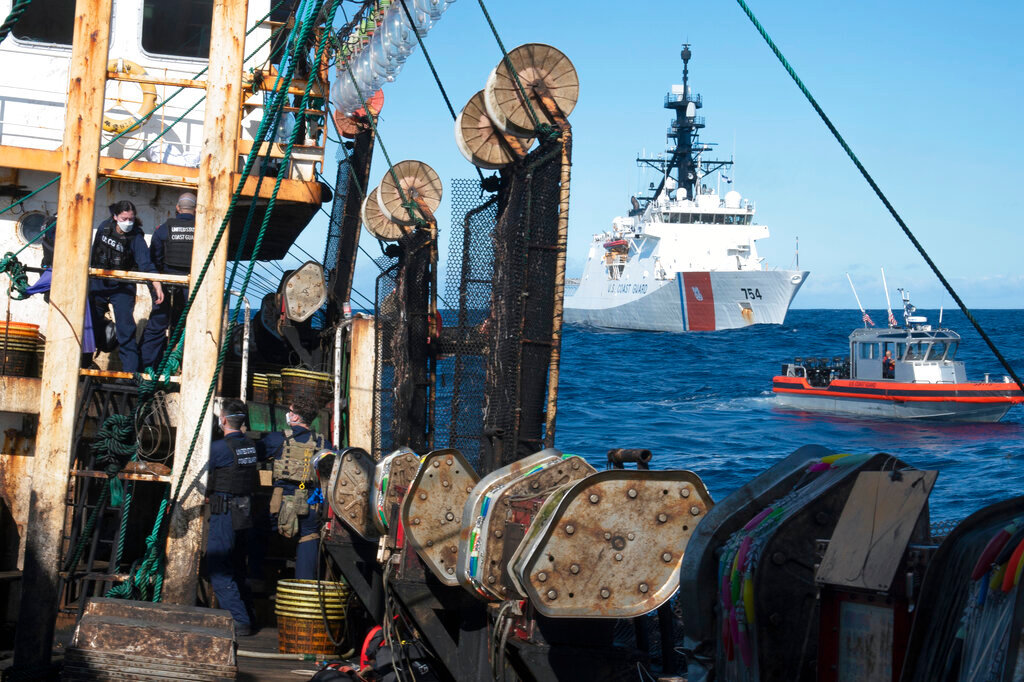 U.S. Coast Guardsmen from the cutter James, seen at background right, conduct a boarding of a fishing vessel in the eastern Pacific Ocean, on Aug. 4, 2022. (Petty Officer 3rd Class Hunter Schnabel/U.S. Coast Guard via AP)